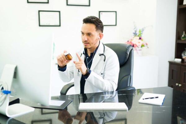 Individual Telemedicine Insurance - Young Doctor Treating a Patient and Explaining Medication Dosage and Side Effects Virtually from the Office